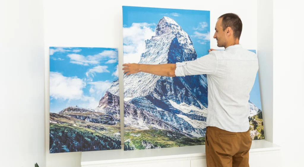 A person setting up canvas prints of a mountain